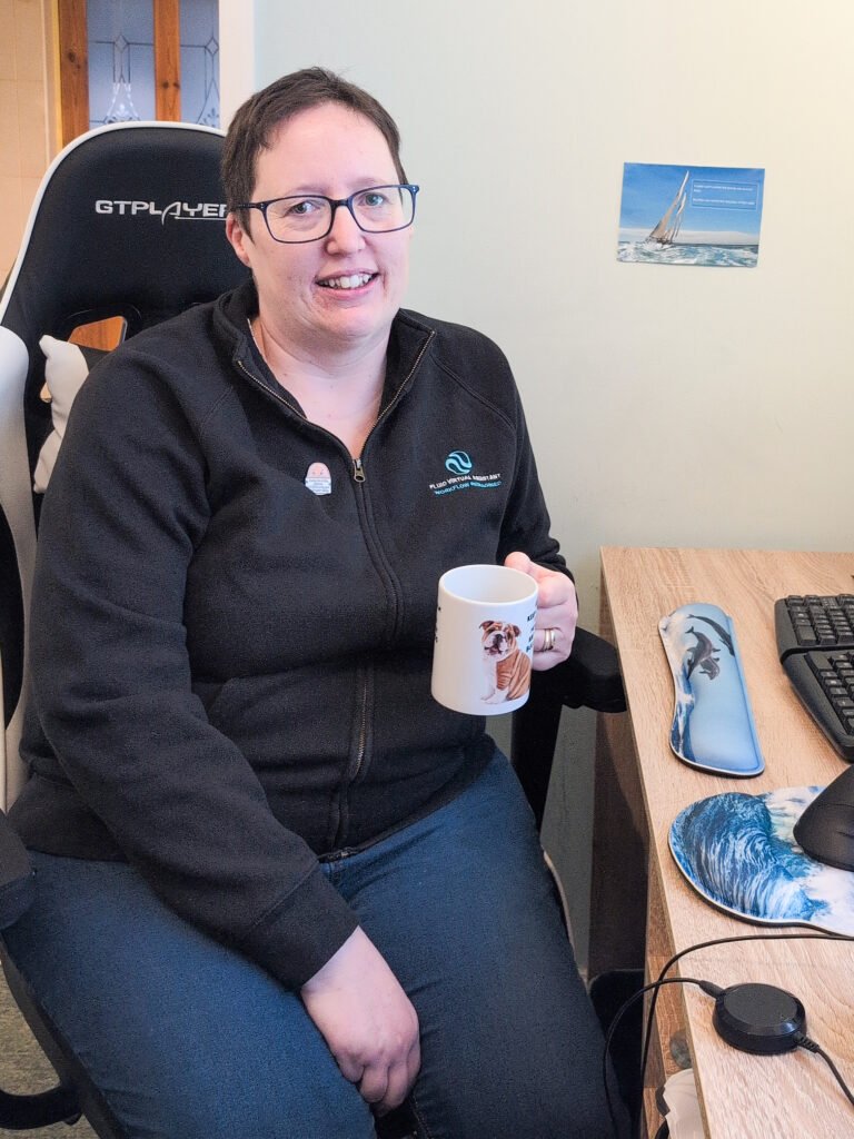 picture of Fluid Virtual Assistant by her desk holding her bulldog mug.